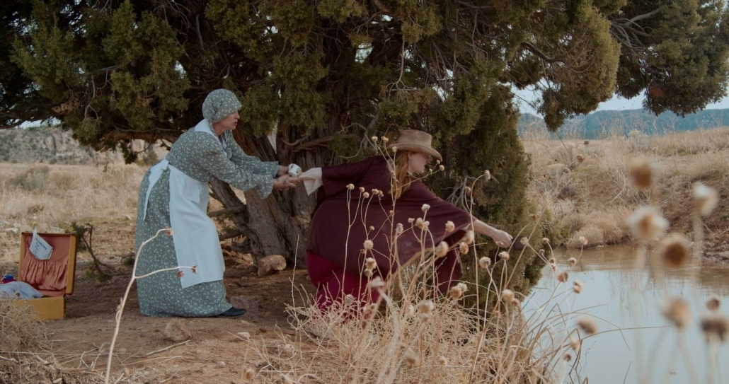 emma holds lily while she reaches toward a stream